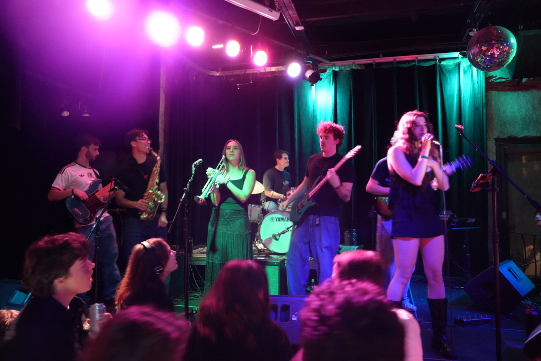 The band on stage under pink lights, Olivia Zegers singing